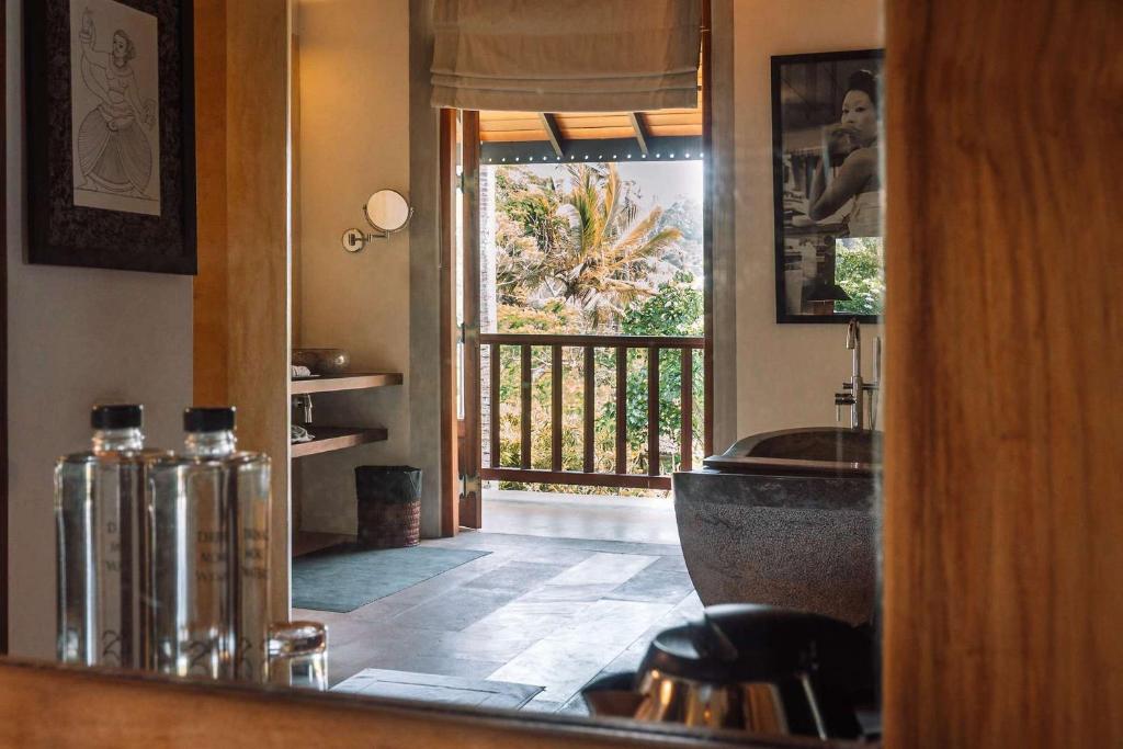 ein Badezimmer mit Badewanne und Blick auf ein Fenster in der Unterkunft Eraeliya Villas & Gardens in Weligama