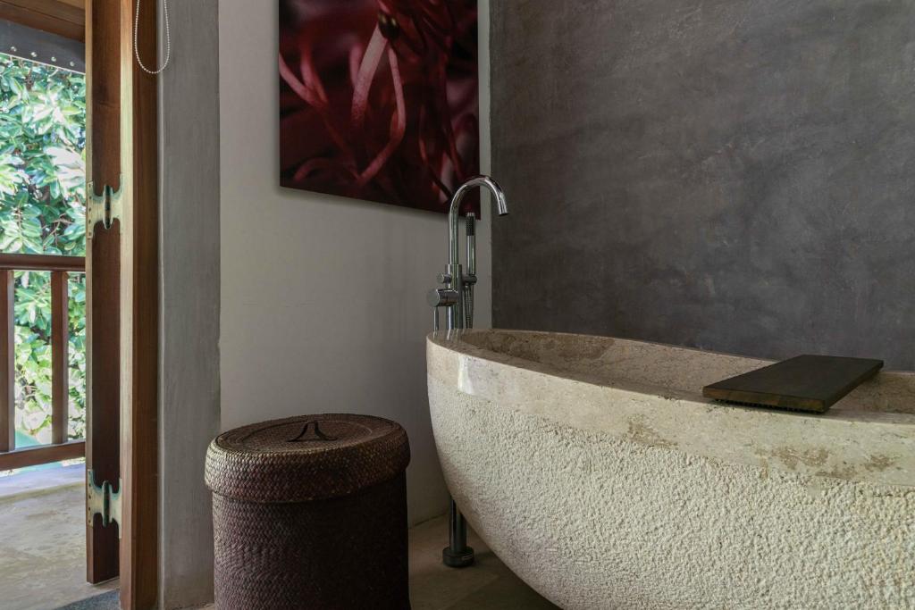 a bath tub in a bathroom with a painting at Eraeliya Villas & Gardens in Weligama