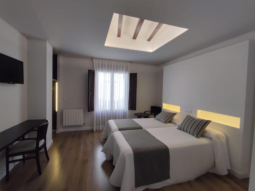 a hotel room with two beds and a desk at Hotel La Vera Cruz in Caravaca de la Cruz