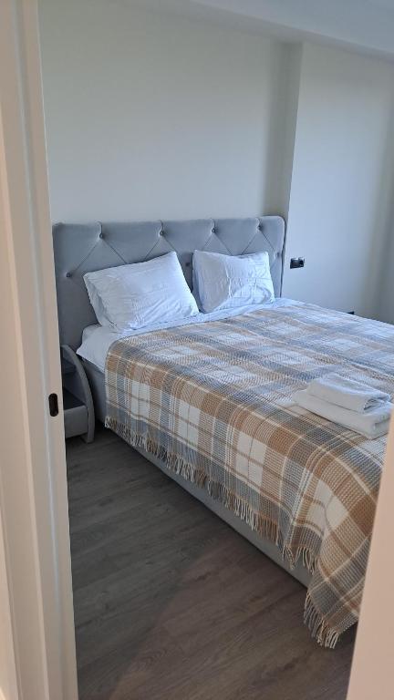 a bed with a plaid blanket and pillows on it at Airport-apartament 24&24 Chişinău!!! in Chişinău