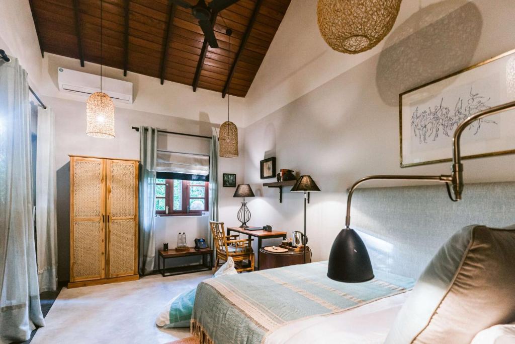 a bedroom with a bed and a desk at Eraeliya Villas & Gardens in Weligama