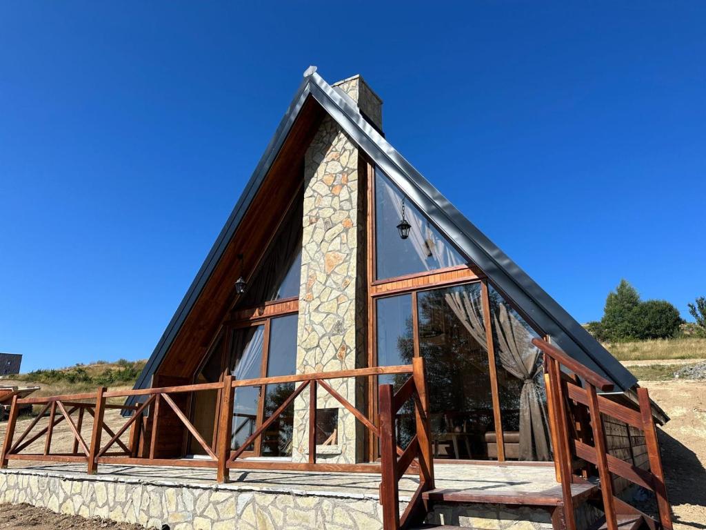 a frame cabin with glass windows and a gambrel roof at Villa deluxe n'Bjeshkë in Dragash