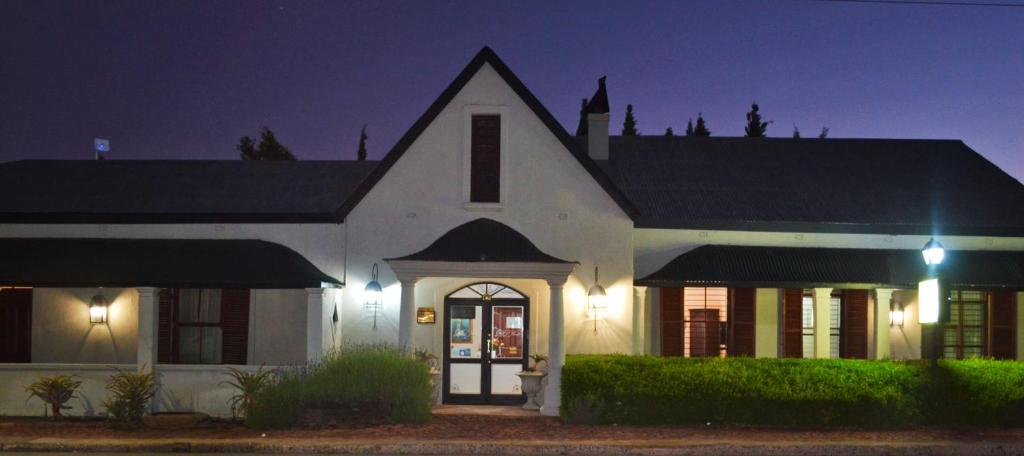 a white house at night with lights at Old House Lodge in Beaufort West