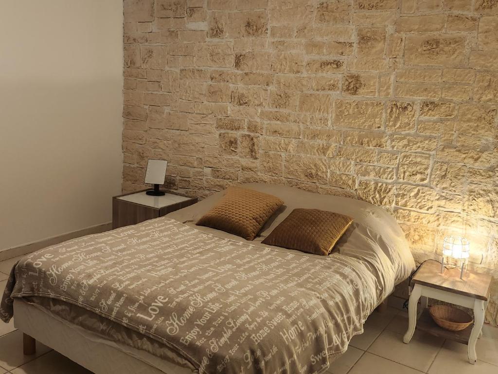 1 dormitorio con cama y pared de ladrillo en Maison tout confort, en Nimes