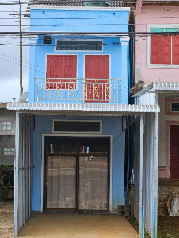 a blue building with red doors and a balcony at Paksong Brand New- Two-story house in Muang Pakxong