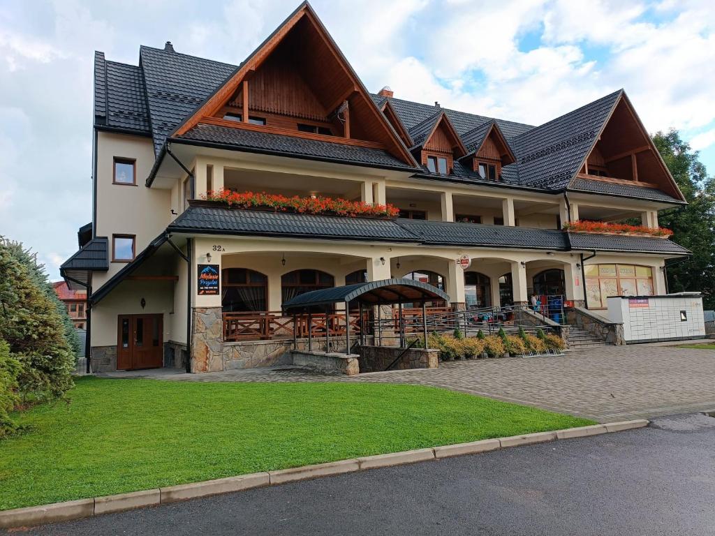 a large building with a roof with flowers on it at Miętusia Przystań - Wynajem Pokoi in Ciche