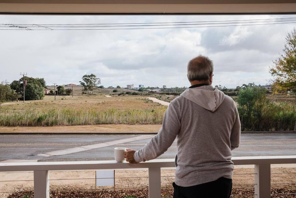 a man holding a coffee cup looking out the window at Long Island Retreat II (by the river with wi-fi) in Murray Bridge