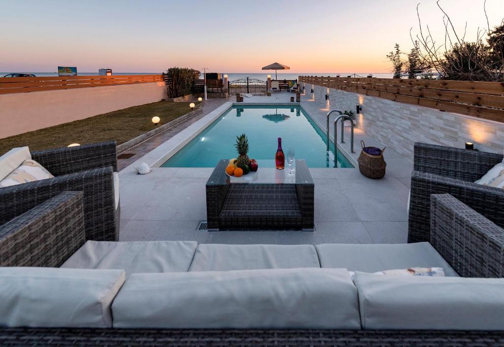 a pool with a couch and a table with a bottle of wine at Villa Fay in Lardos