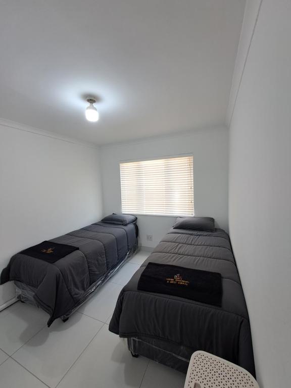 a bedroom with three beds and a window at North beach summer sands holiday in Durban