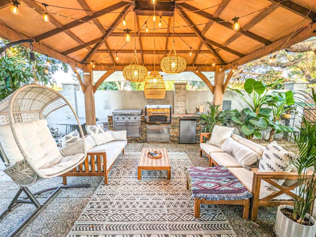 an outdoor patio with a couch and chairs and a table at Casita Hosum: Modern WFH Garden Suite w/ Gazebo Outdoor Kitchen & BBQ in San Jose