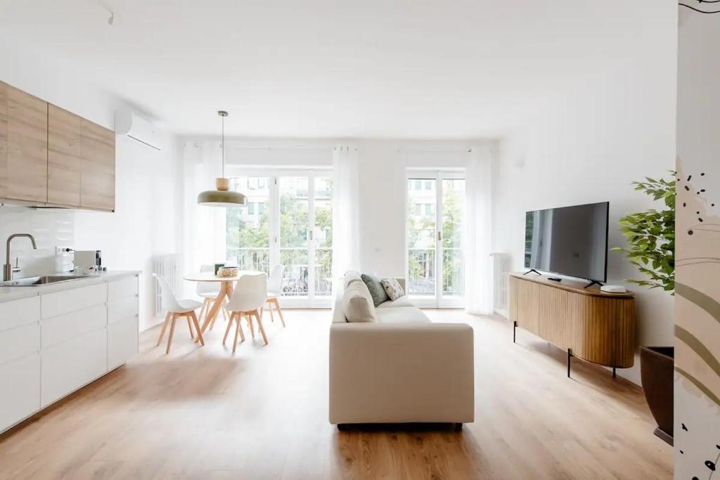 a white living room with a white couch and a kitchen at Luxury 2 bedroom Apartament, close to San Siro, Fiera and 10 min metro to Duomo in Milan