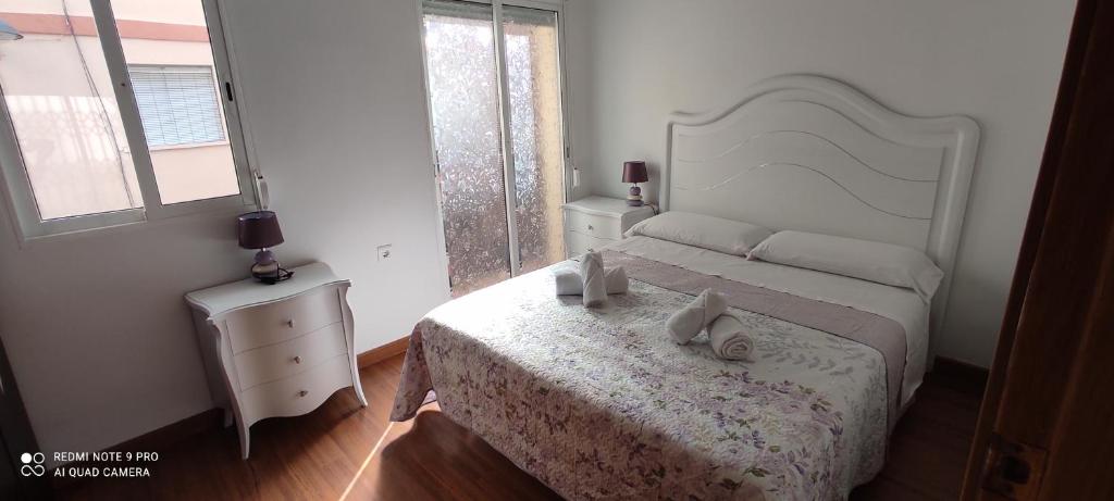 un dormitorio con una cama blanca con zapatos. en Mi pequeña terraza, en Alacuás