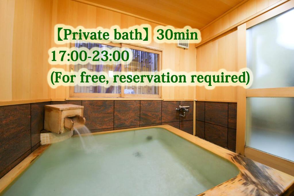 La salle de bains est pourvue d'une baignoire et d'un panneau. dans l'établissement Ryokan Kamogawa Asakusa, à Tokyo