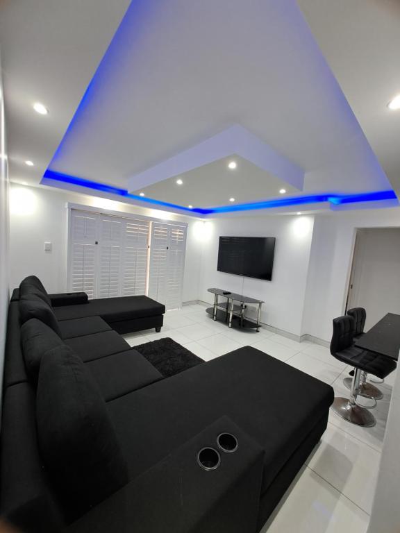 Una sala de estar con un sofá negro y un televisor de pantalla plana. en Summer sands north beach, en Durban