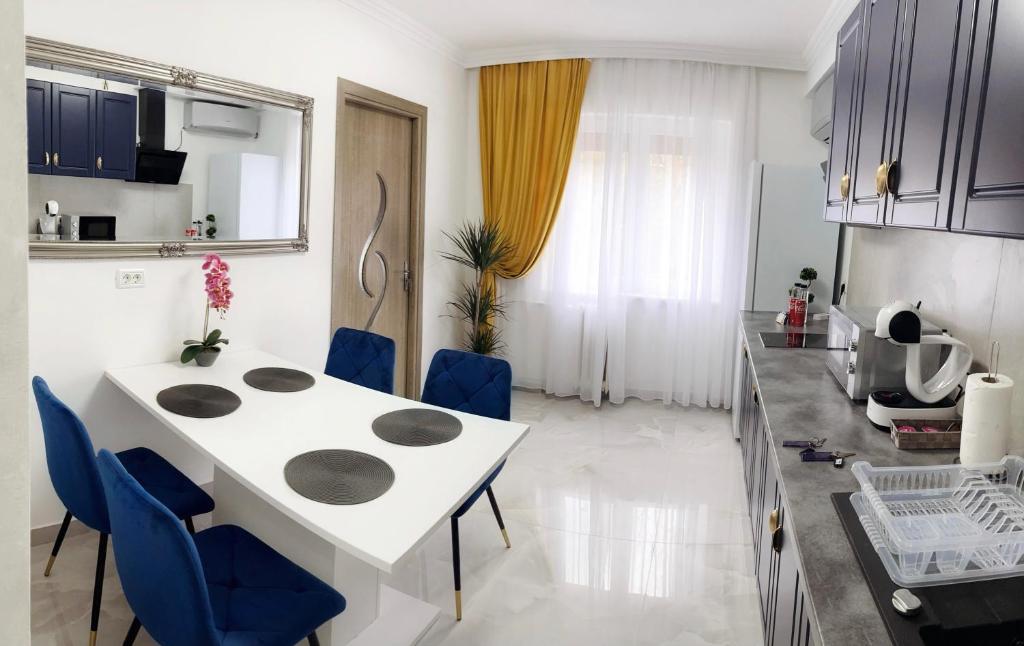 una cucina e una sala da pranzo con tavolo bianco e sedie blu di Apartament Premium Isabella a Arad