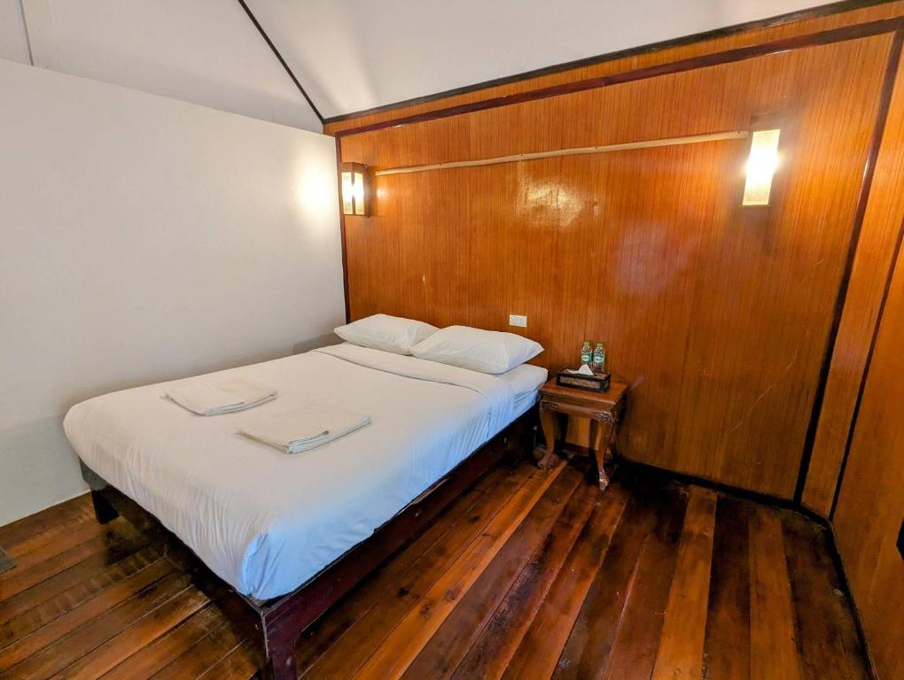 - une chambre avec un lit et un mur en bois dans l'établissement Ziggy Stardust, à Ko Phayam