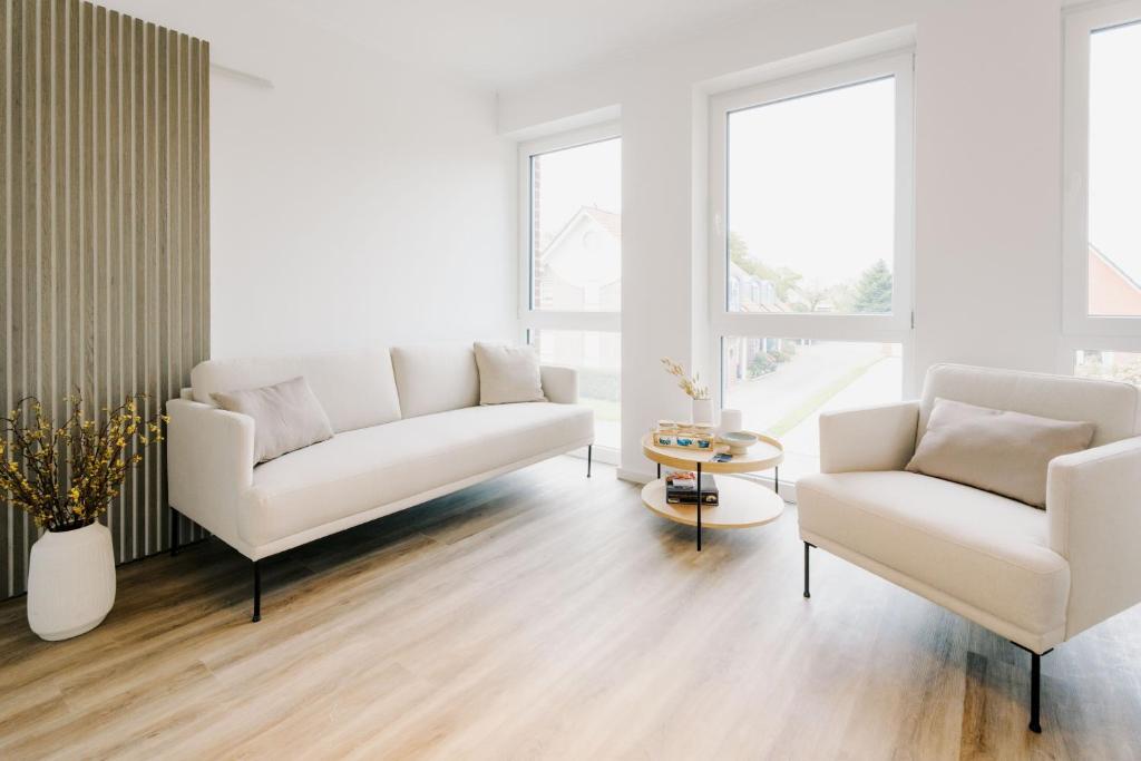 a living room with two white couches and a table at Küsten Suite de See - Suite 4 seitliche Deichlage, Balkon, 89qm in Greetsiel