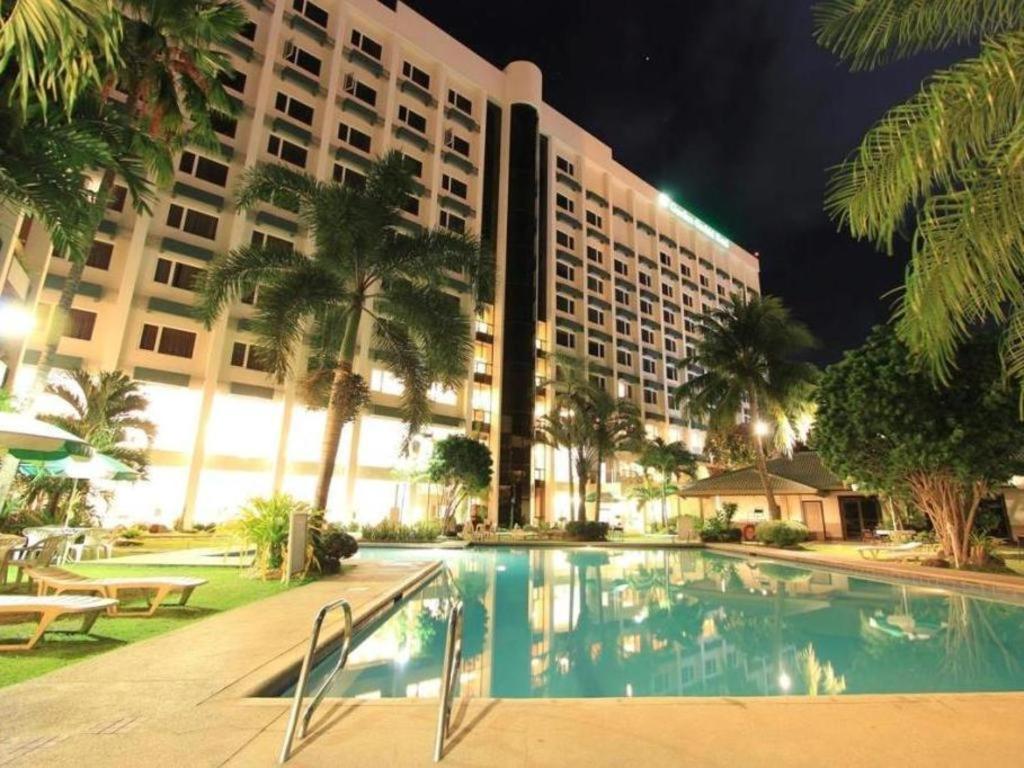 a hotel with a swimming pool in front of a building at Garden Orchid Hotel 