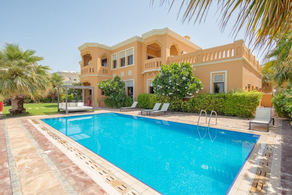 a villa with a swimming pool in front of a house at Maison Privee - Prvt Pool & Beach Access in Luxury Palm Jumeirah 6BR Villa in Dubai