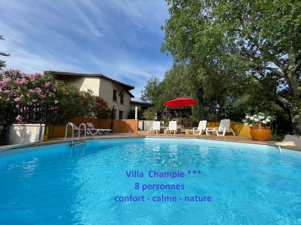 uma piscina com cadeiras e um guarda-sol vermelho em Villa Champie em Pradons