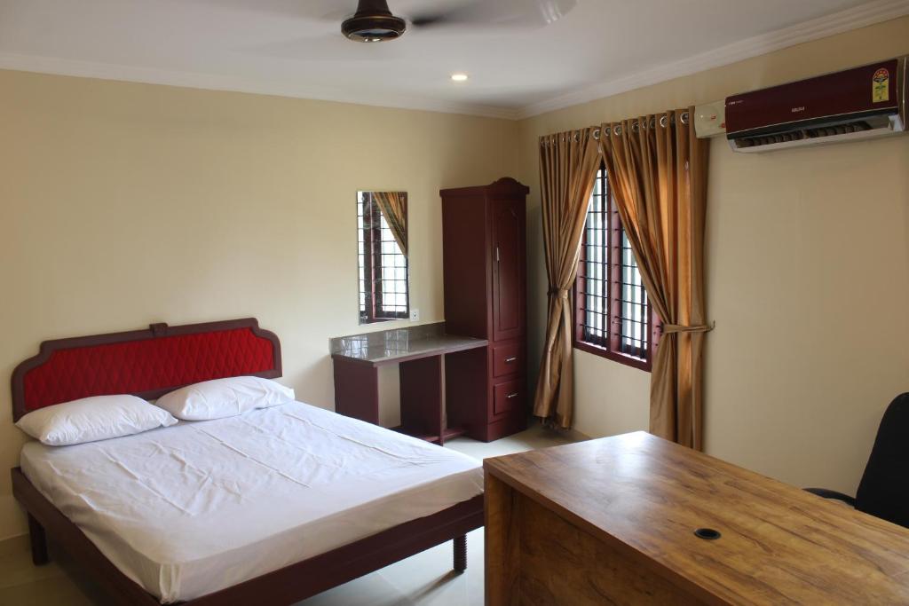 a bedroom with a bed and a wooden table at LILLY RESIDENCY by Chungath in Perumbavoor