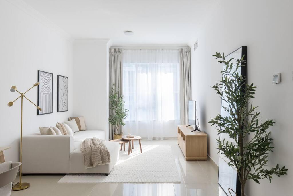 a white living room with a white couch and a window at COLIFE 21 floor, 7 min drive from Dubai Mall 136 in Dubai