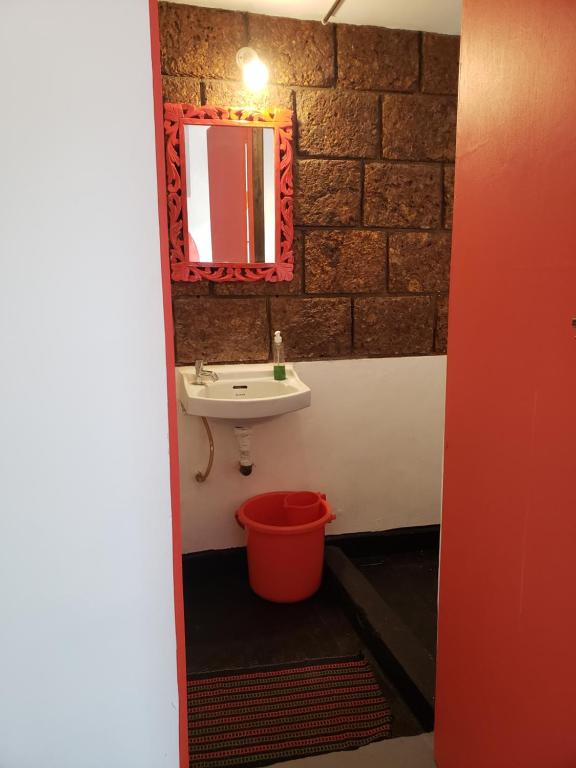 a bathroom with a sink and a red bucket at Laxmi Happy Home in Querim Goa in Querim