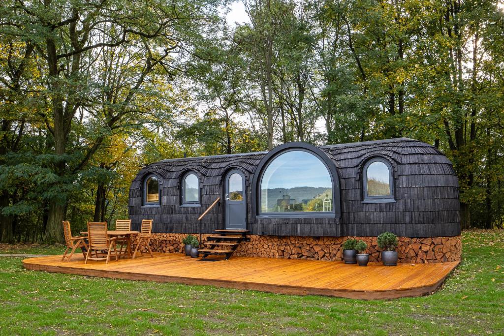 una pequeña casa negra con una terraza de madera en un patio en Glamping Skrytín 