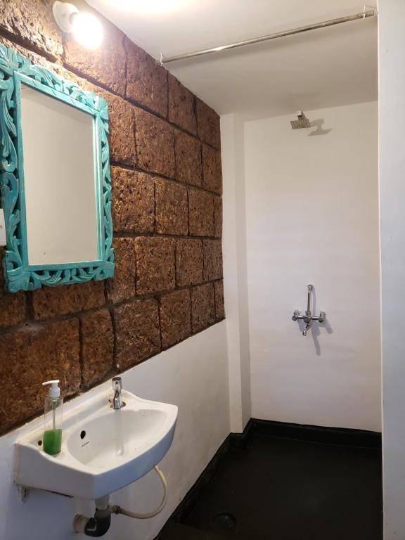 a bathroom with a sink and a mirror on a brick wall at Laxmi Happy Home in Querim Goa in Querim