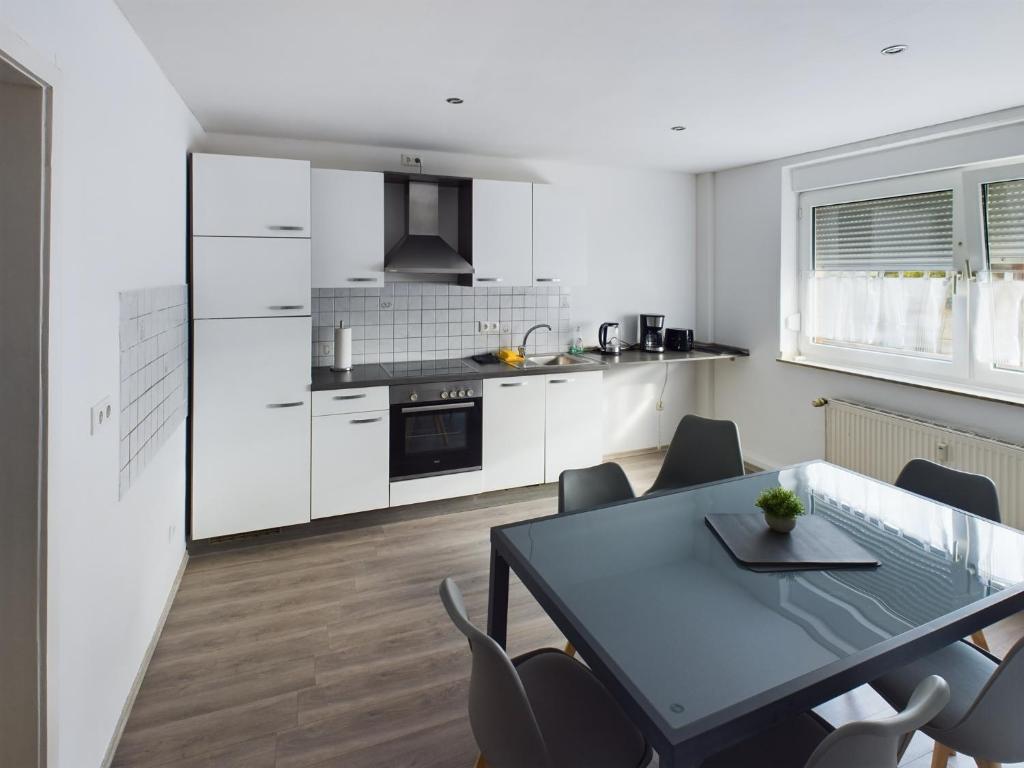 アルスドルフにあるAldorf 4の白いキャビネット、テーブルと椅子付きのキッチンが備わります。