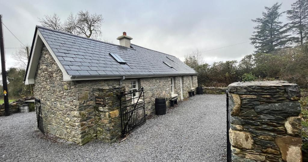 Teernaboul的住宿－Newly Renovated stone cottage located 2.5 miles from Killarney Town，一座石头建筑,有黑色的屋顶和门