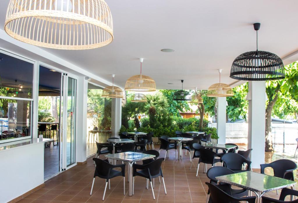 un restaurante con mesas, sillas y ventanas grandes en Càmping Bellsol, en Pineda de Mar