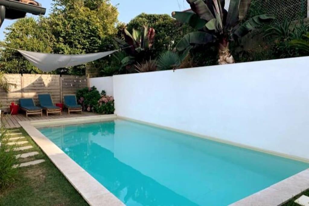 een zwembad in een tuin naast een hek bij Jolie villa avec piscine chauffée in Anglet
