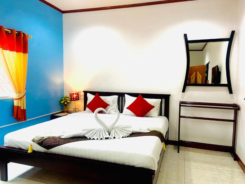 a bedroom with a bed with red and white pillows at Lanta Grand House in Ko Lanta