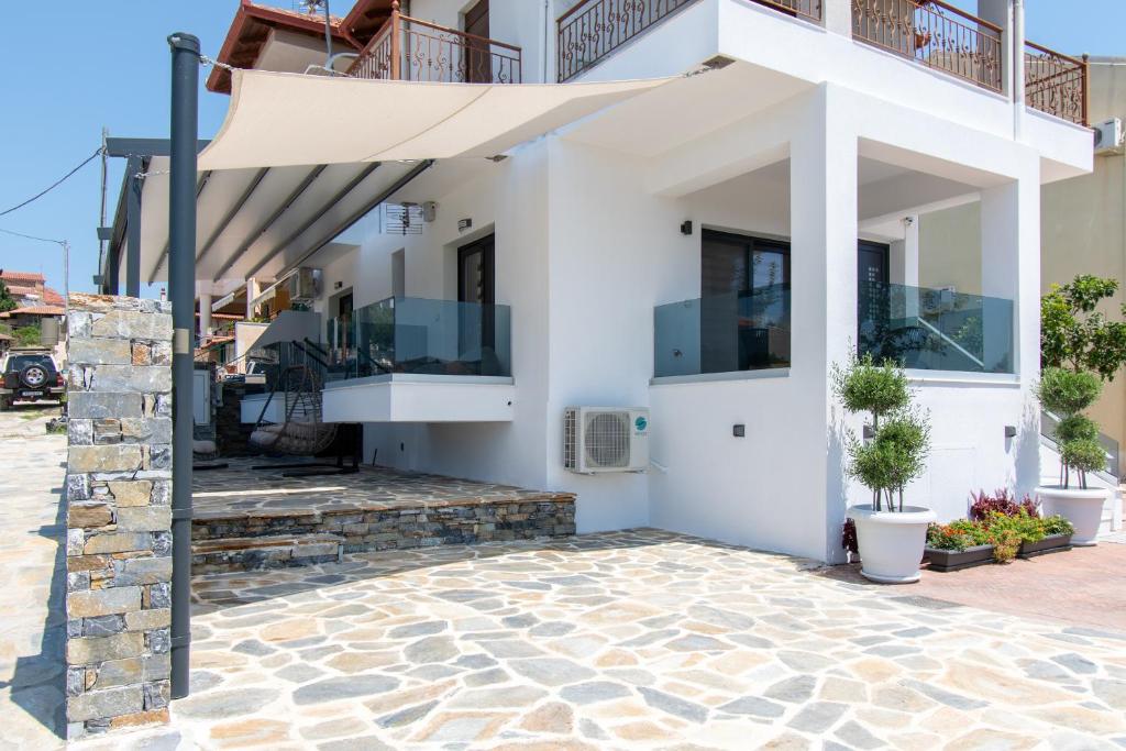 a white house with a balcony and a patio at SithoniaRS Melora Luxury Apartment in Nikiti