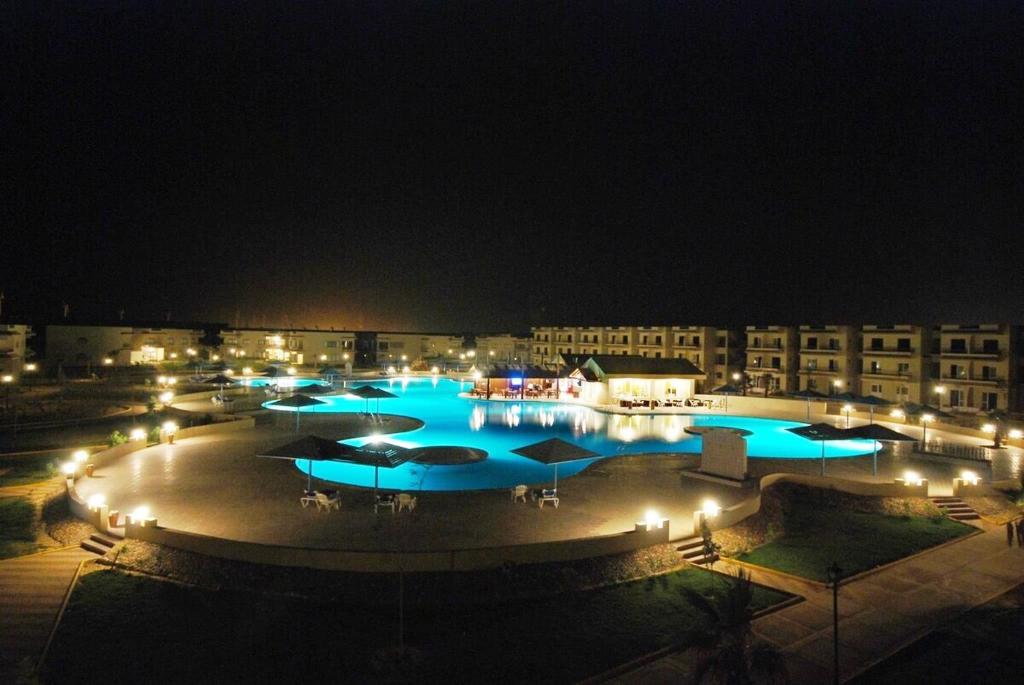 ein großer Pool in der Nacht mit blauen Lichtern in der Unterkunft Regina Resort El Sokhna in Ain Suchna