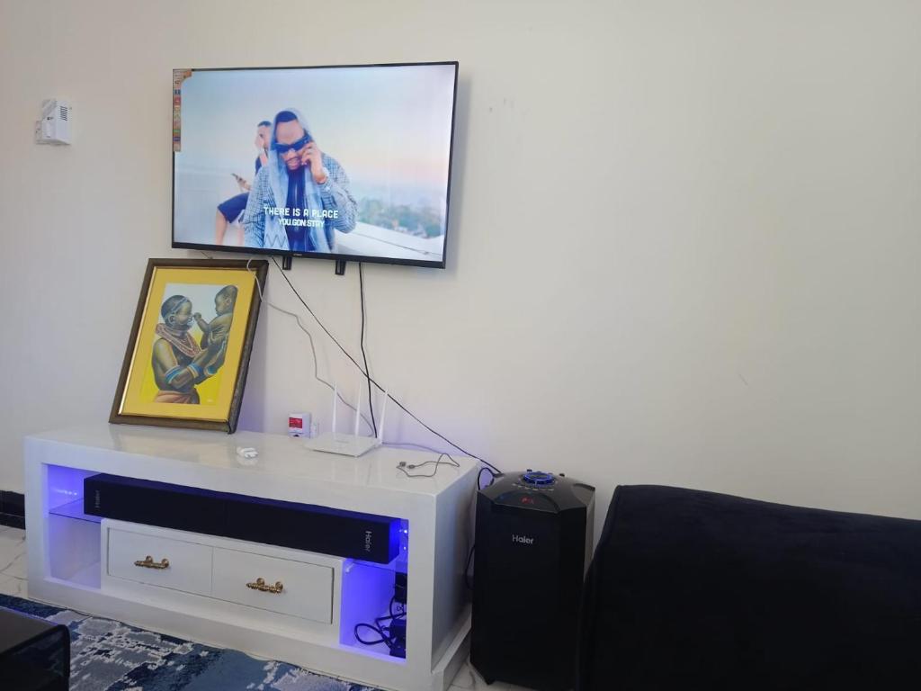 un televisor en una pared sobre un tocador con una foto en TWO BEDROOM APARTMENT BAMBURI Mombasa en Mombasa