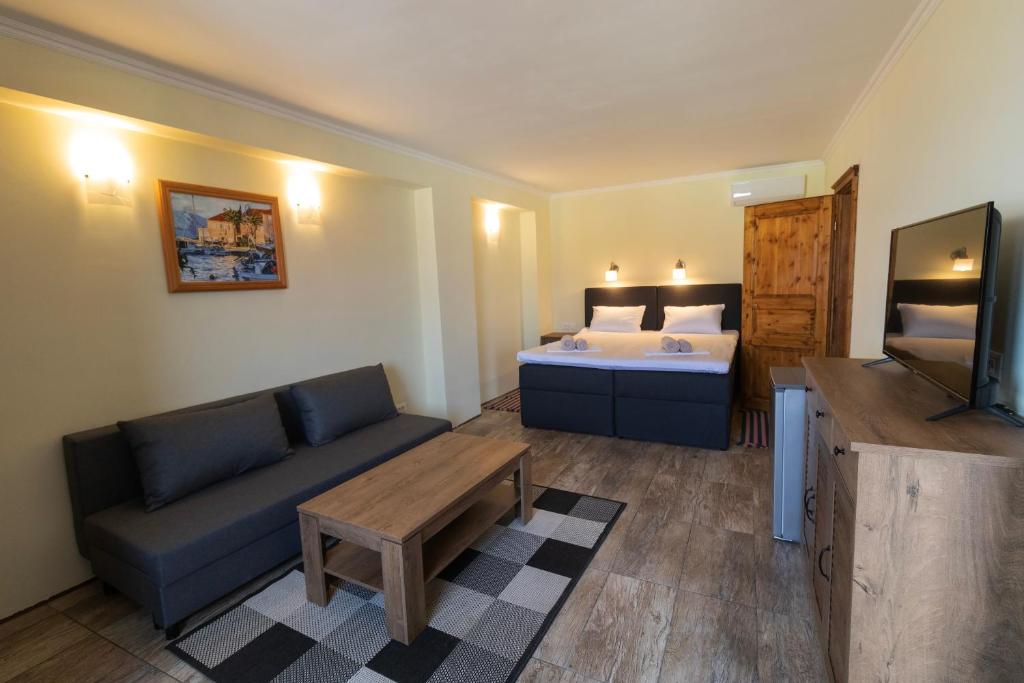 ein Wohnzimmer mit einem Sofa, einem Bett und einem TV in der Unterkunft Taverna & Rooms in Sutivan