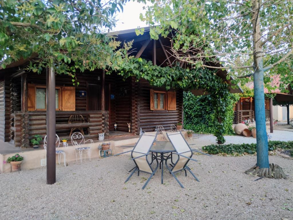 una mesa y sillas frente a una cabaña de madera en Casas Rurales Villa Pereza, en Casas de los Pinos