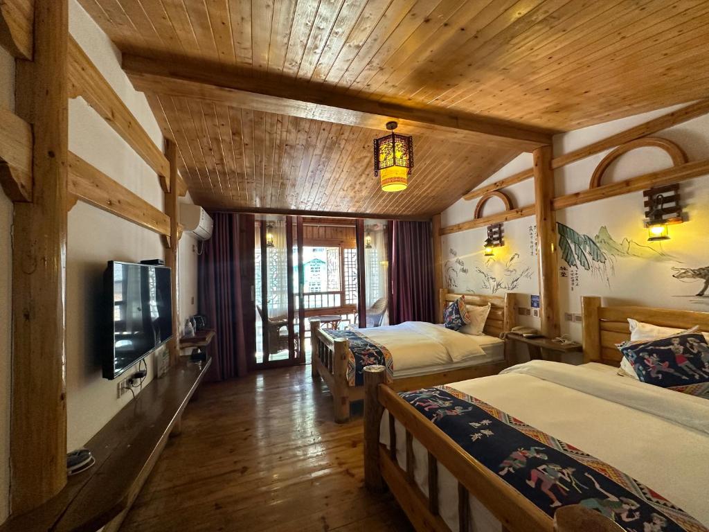 a hotel room with two beds and a tv at Mountain View Guesthouse in Zhangjiajie
