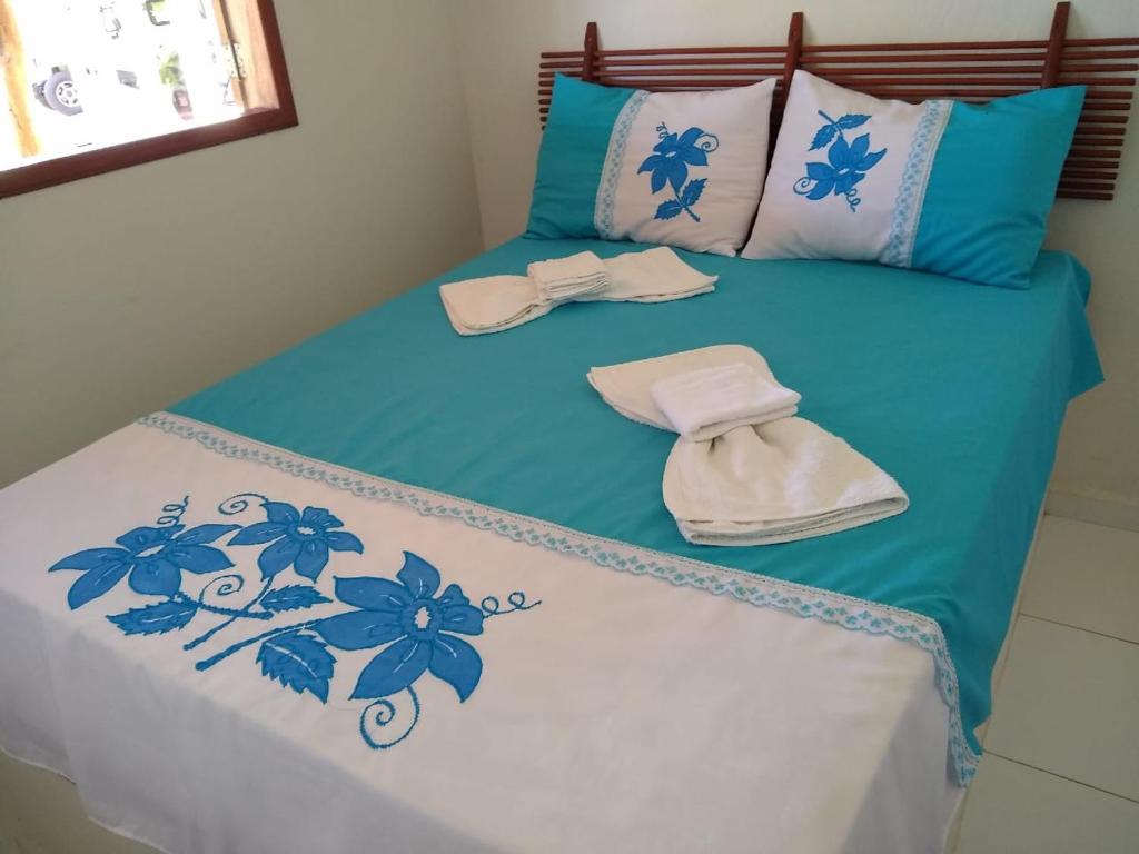 a bed with blue and white sheets and towels on it at Condomínio e Pousada Chalés Sossego do Gostoso in São José