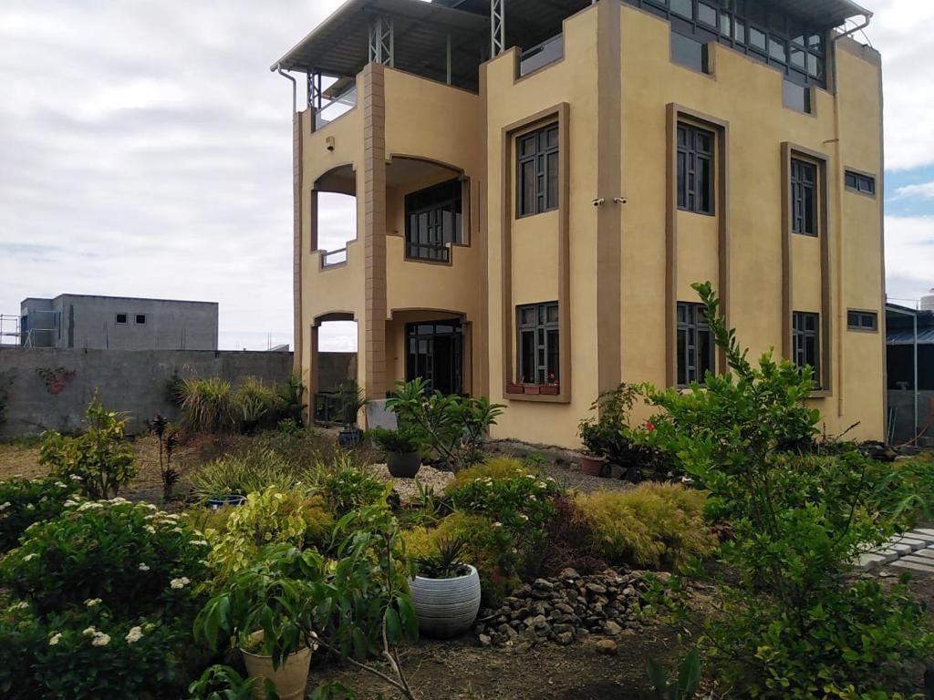un grand bâtiment jaune avec des plantes devant lui dans l'établissement Residence Neerabelle, à Centre de Flacq