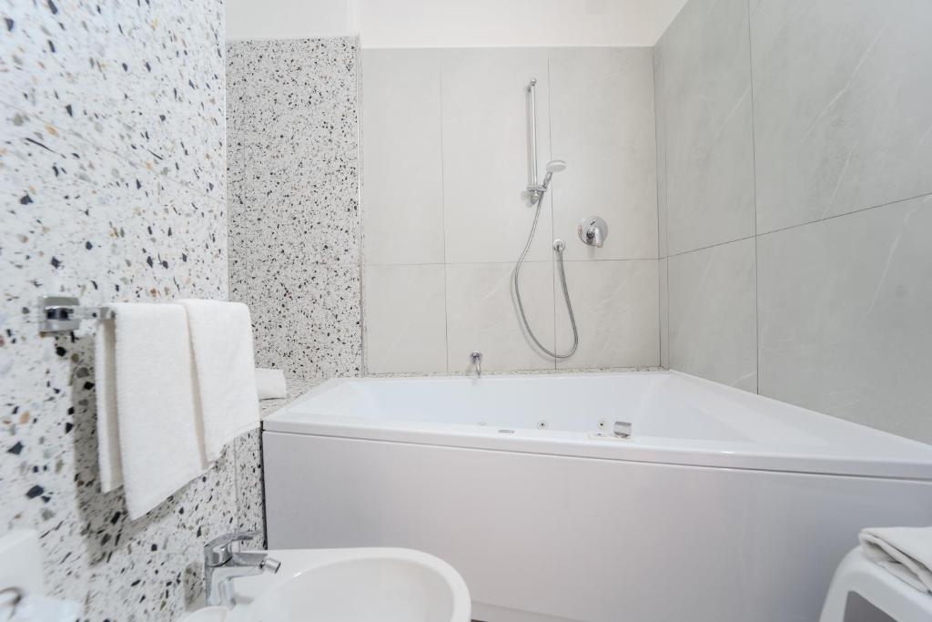 a white bathroom with a tub and a sink at Hotel Donatello in Modena