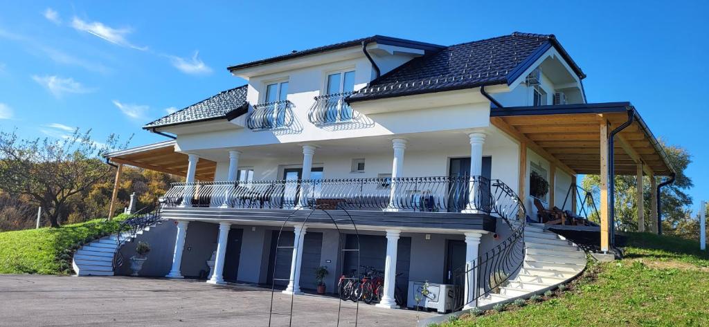 een groot wit huis met een groot balkon bij Villa Hojnik in Videm pri Ptuju