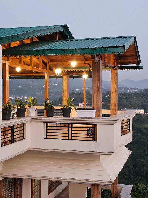 a building with a deck with potted plants on it at Laspa Cottage, Bhimtal in Bhīm Tāl