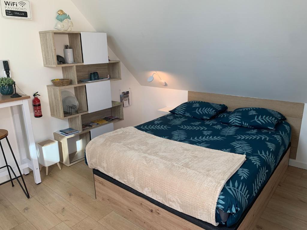 a bedroom with a bed with a blue comforter at La Pose Normande in La Cerlangue