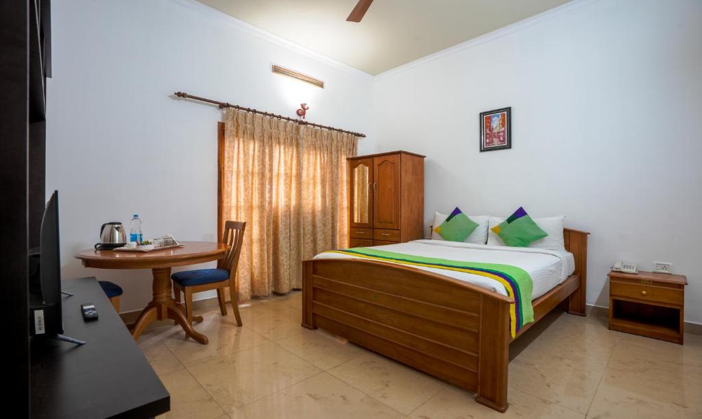 a bedroom with a bed and a table and a desk at Itsy By Treebo -Classiyo Munnar Crown Resorts in Munnar