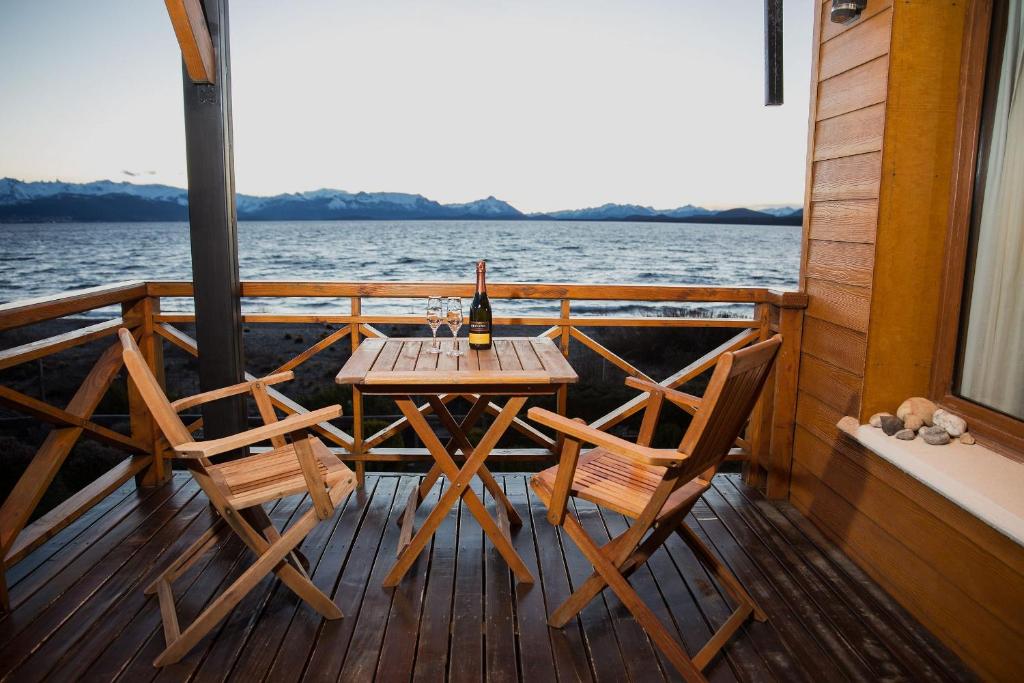 una terraza de madera con mesa y sillas en un barco en Blue Aparts Dina Huapi Bariloche en Dina Huapi