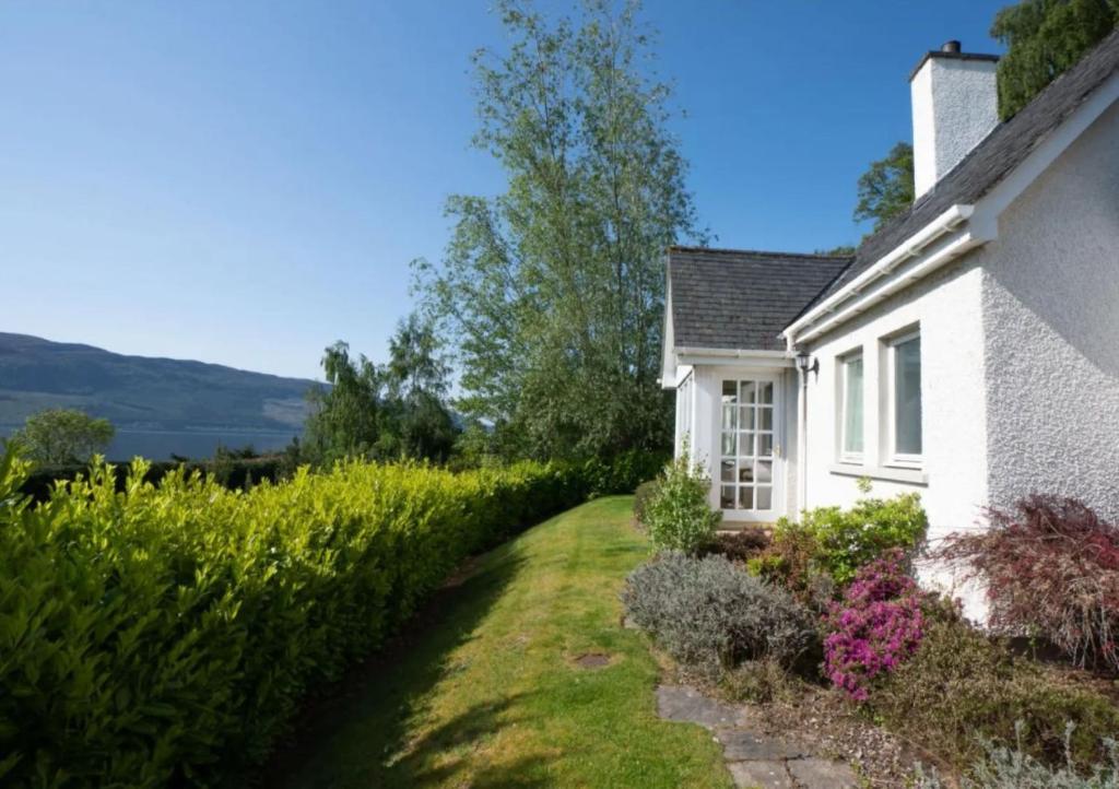 a white house with a garden in front of it at Loch Ness Cottages in Brackla
