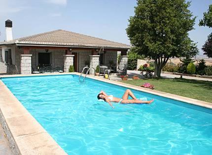 a woman is laying in a swimming pool at Casa rural EL CASTILLO DE CIRUELAS in Ciruelas